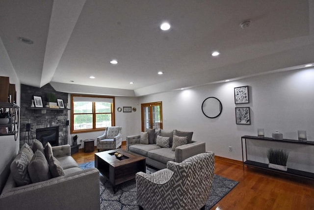 living room with a stone fireplace and wood-type flooring