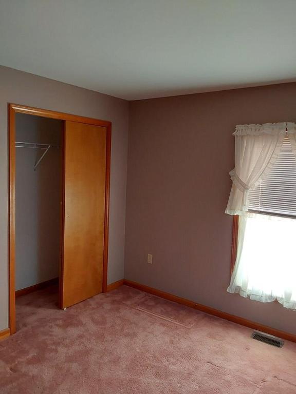 unfurnished bedroom featuring light carpet and a closet