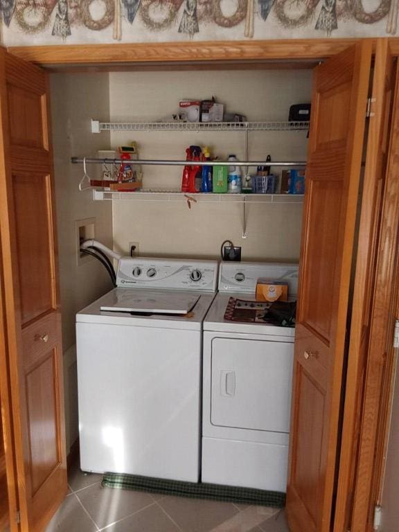 clothes washing area featuring tile patterned flooring and washer and dryer