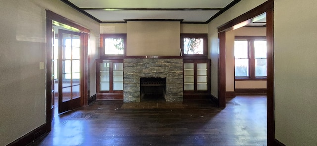 unfurnished living room featuring ornamental molding, a stone fireplace, dark hardwood / wood-style flooring, and a wealth of natural light