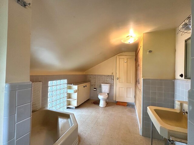 bathroom featuring vaulted ceiling, sink, tile walls, a washtub, and toilet