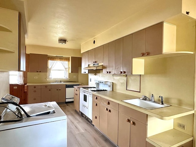 kitchen with sink, white appliances, backsplash, washer / dryer, and light wood-type flooring