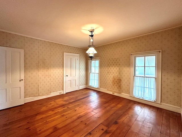 empty room featuring wood-type flooring and ornamental molding