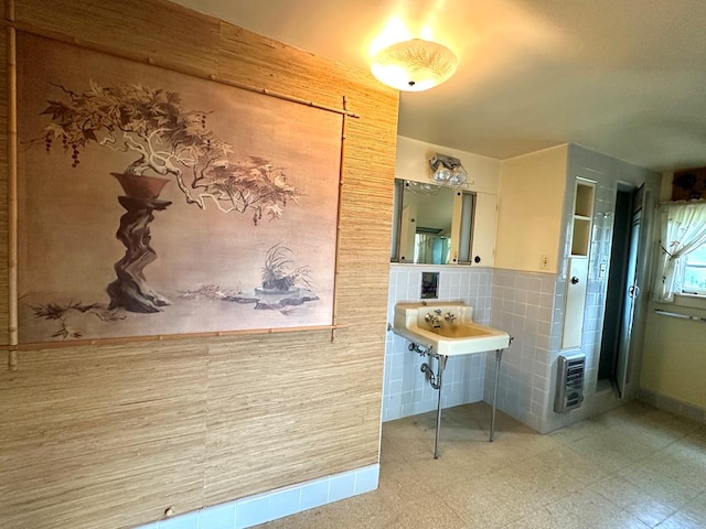 bathroom with sink, heating unit, and tile walls