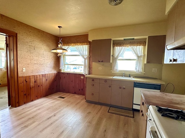 kitchen featuring white appliances, decorative light fixtures, sink, and a wealth of natural light