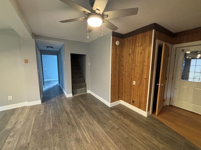 spare room featuring dark hardwood / wood-style floors, ceiling fan, and wood walls