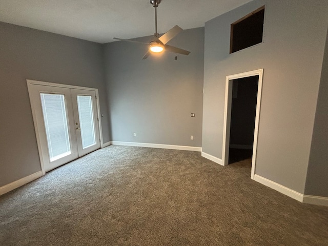 carpeted empty room with a towering ceiling, french doors, and ceiling fan