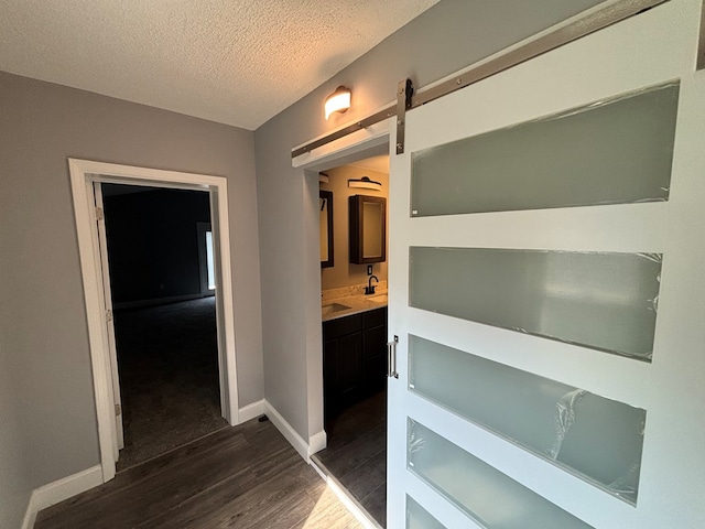 corridor with dark hardwood / wood-style floors, a barn door, and a textured ceiling