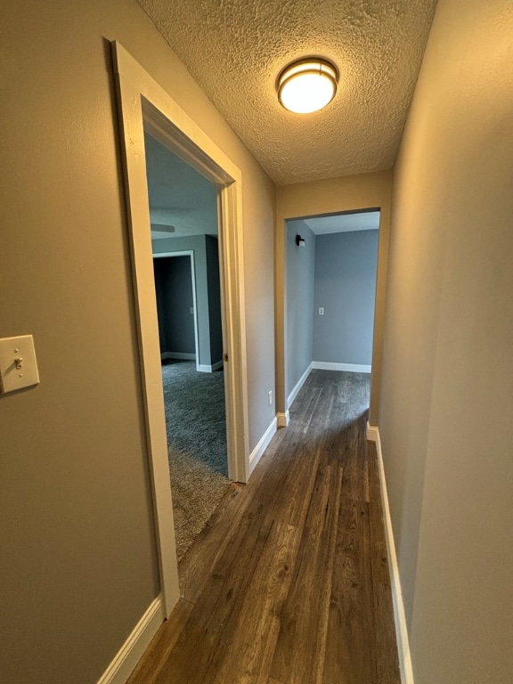 hallway with dark hardwood / wood-style floors and a textured ceiling