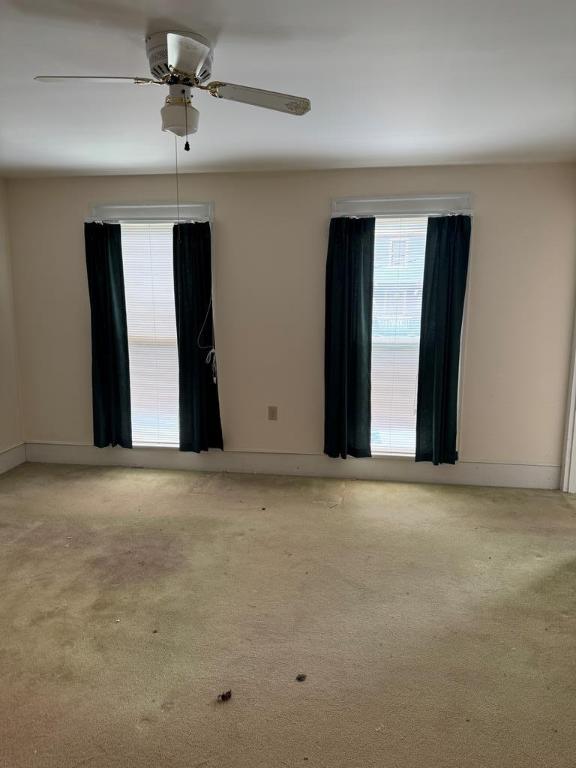 empty room with ceiling fan and light carpet