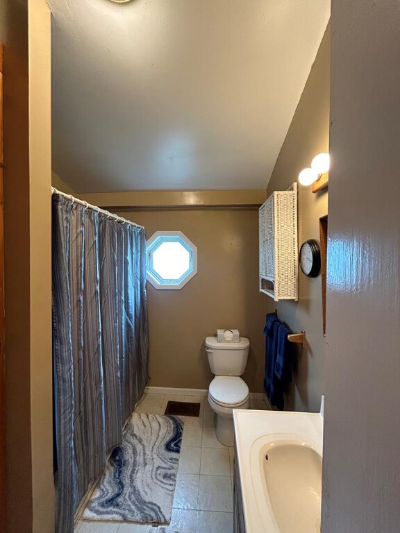 bathroom with vaulted ceiling, vanity, toilet, tile patterned floors, and a shower with curtain