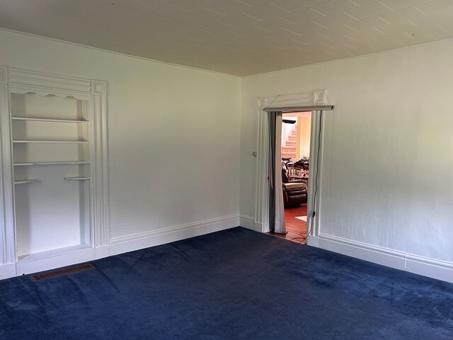 carpeted empty room featuring built in shelves