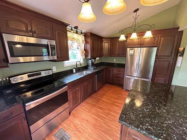 kitchen with lofted ceiling, sink, hanging light fixtures, light wood-type flooring, and stainless steel appliances