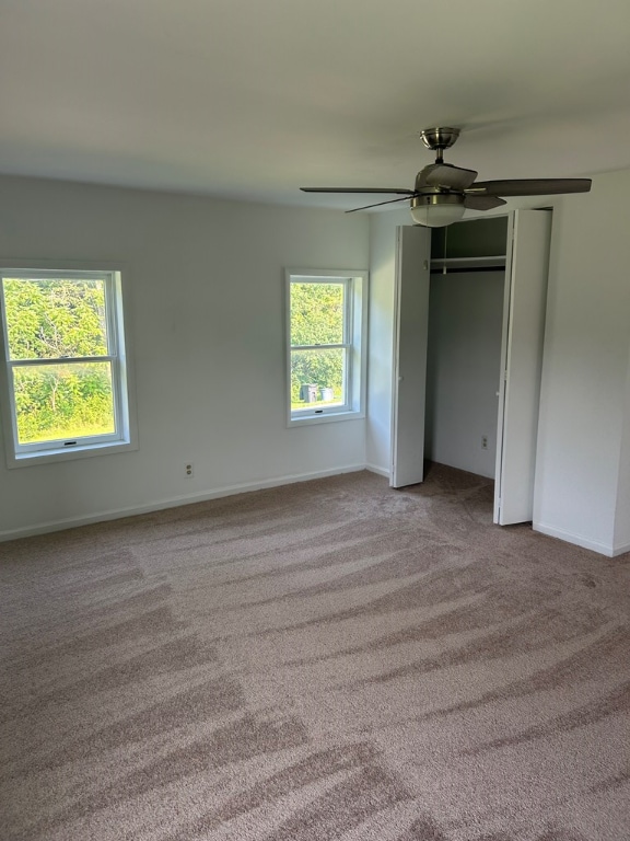 unfurnished bedroom featuring ceiling fan, light colored carpet, and multiple windows