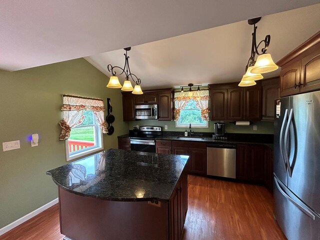 kitchen featuring appliances with stainless steel finishes, sink, hanging light fixtures, a center island, and dark brown cabinets