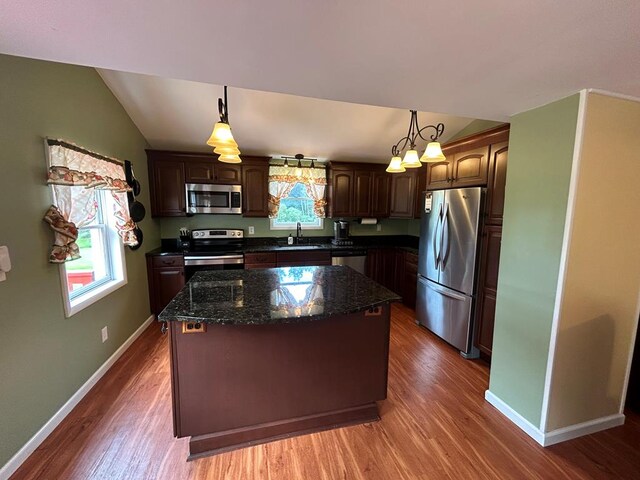 kitchen with stainless steel appliances, decorative light fixtures, sink, and a kitchen island