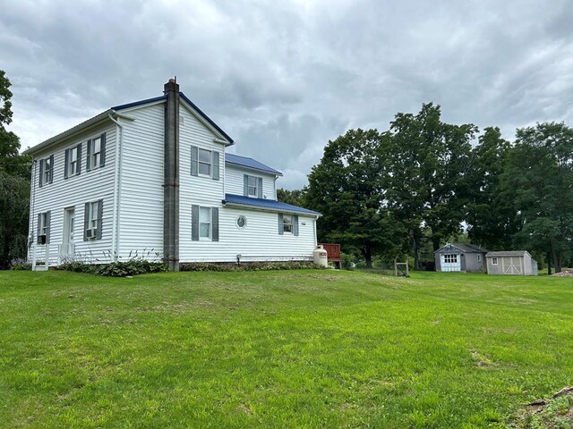 rear view of house featuring a storage shed and a yard