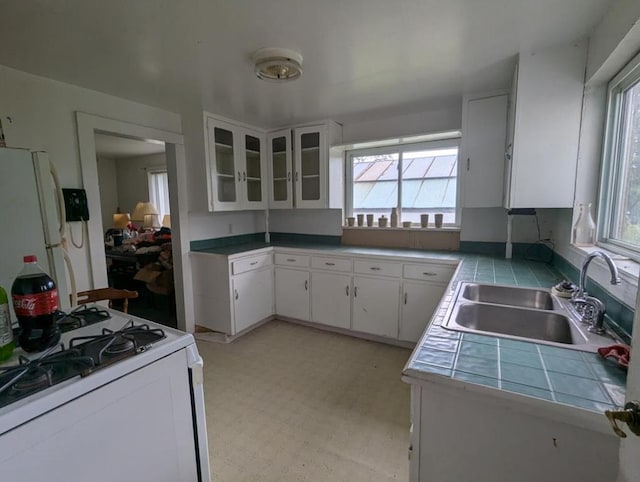 kitchen with white cabinetry, sink, white appliances, and a healthy amount of sunlight