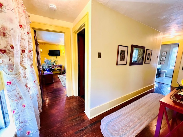 corridor with a textured ceiling and dark hardwood / wood-style floors