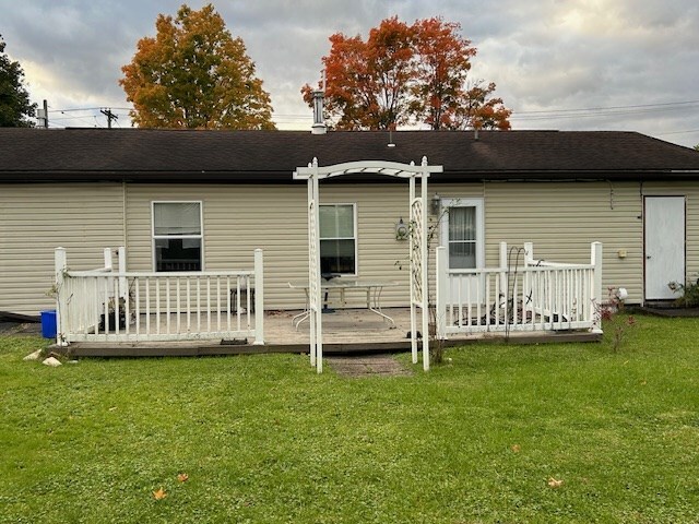 rear view of house with a wooden deck and a lawn