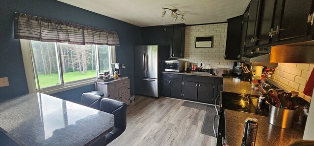 kitchen featuring backsplash, brick wall, appliances with stainless steel finishes, and light wood-type flooring