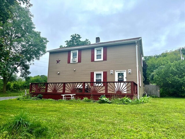 rear view of house with a wooden deck and a lawn