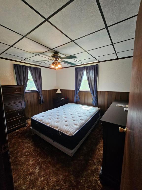 carpeted bedroom with a drop ceiling and wooden walls