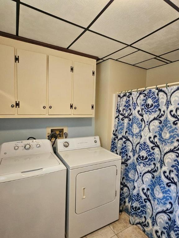 clothes washing area with cabinets, independent washer and dryer, and light tile patterned floors