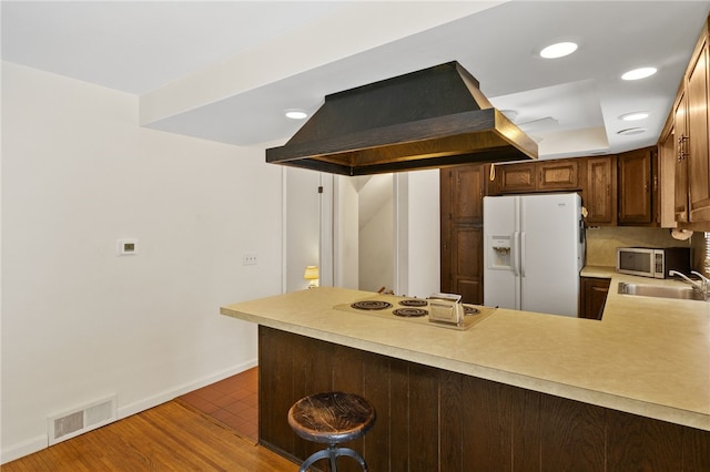 kitchen with sink, island range hood, a kitchen breakfast bar, kitchen peninsula, and white appliances