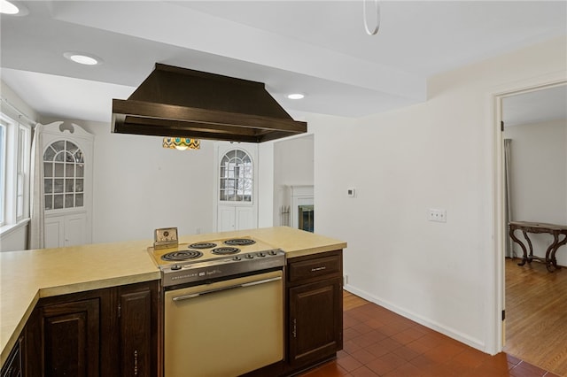 kitchen featuring dark brown cabinetry, dark tile patterned flooring, island range hood, and stainless steel electric stove