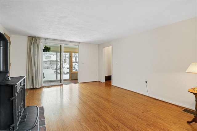 unfurnished living room with light wood-type flooring and a wood stove