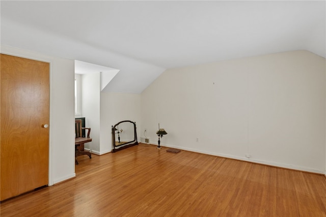 additional living space with hardwood / wood-style flooring and vaulted ceiling