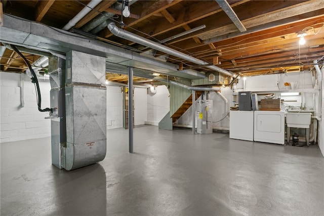 basement with heating unit, water heater, sink, and washer and dryer