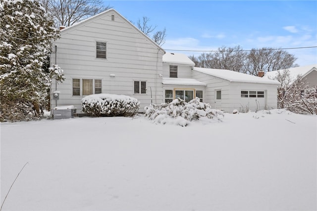 snow covered house featuring a garage