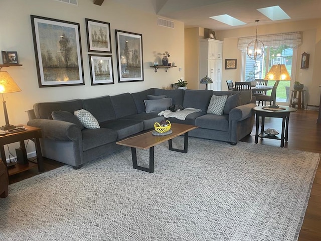 living room featuring a skylight, dark hardwood / wood-style floors, and a chandelier