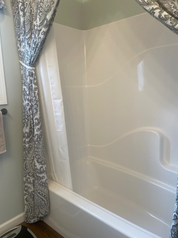 bathroom featuring shower / bathtub combination with curtain and hardwood / wood-style floors