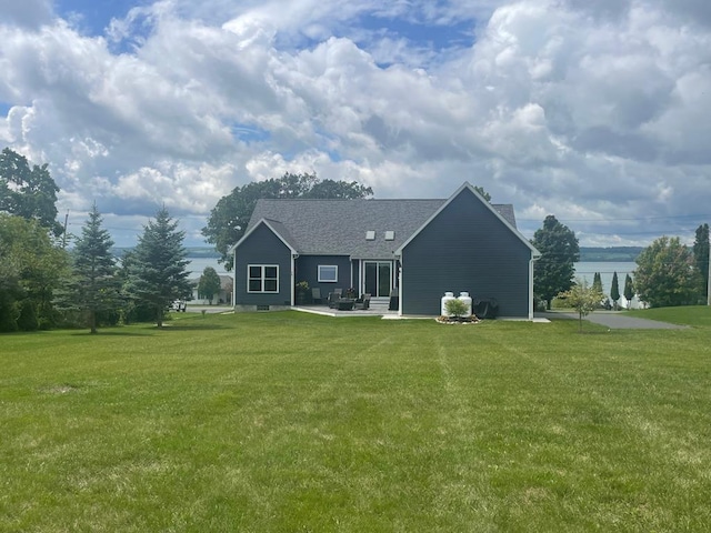 rear view of property featuring a patio, a water view, and a lawn