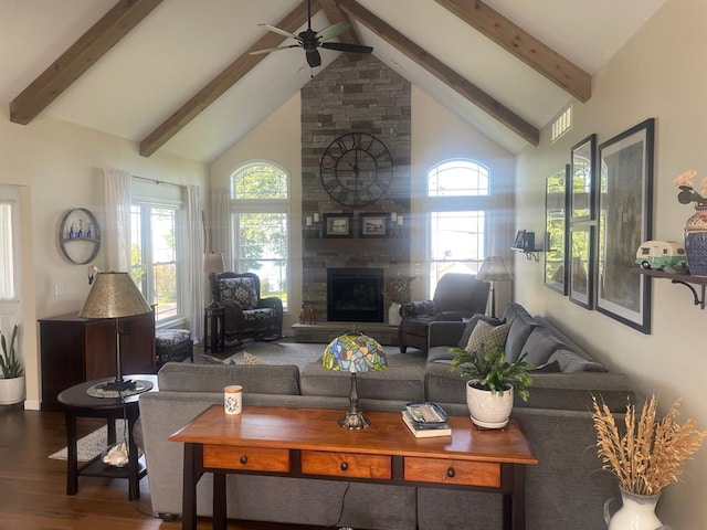 living room with hardwood / wood-style flooring, ceiling fan, high vaulted ceiling, a large fireplace, and beamed ceiling