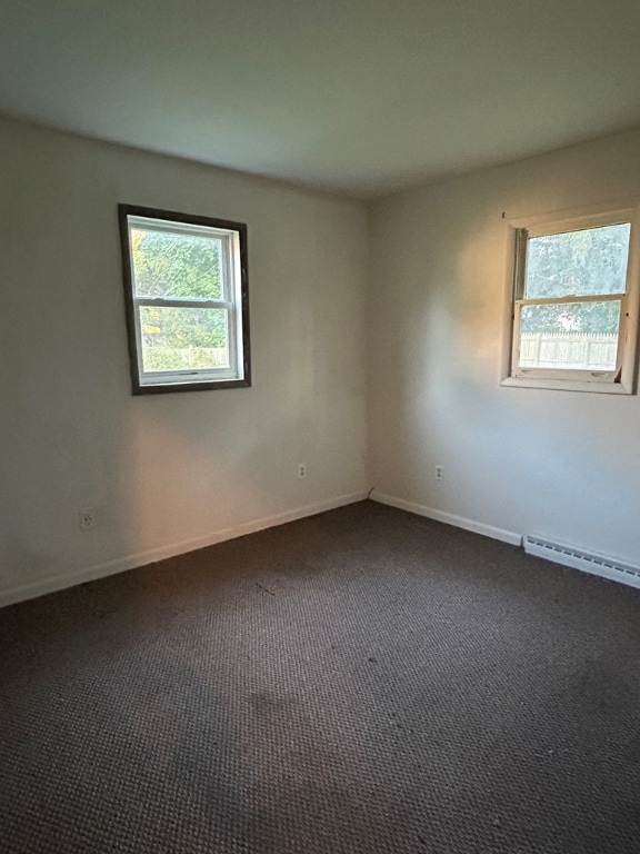 empty room with a baseboard radiator and dark colored carpet