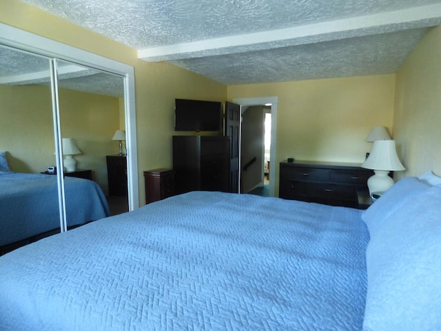 bedroom with beam ceiling, a closet, and a textured ceiling