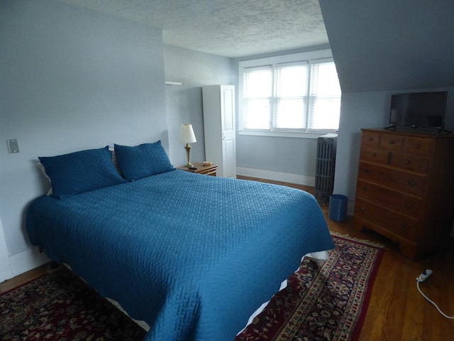 bedroom featuring radiator, hardwood / wood-style floors, and a textured ceiling