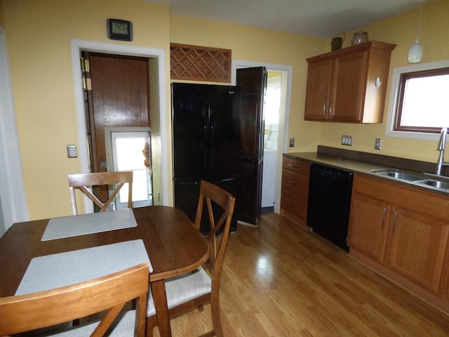 kitchen featuring light hardwood / wood-style floors, sink, black appliances, and hanging light fixtures