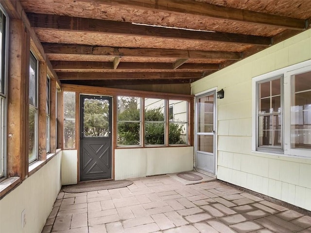 unfurnished sunroom featuring lofted ceiling with beams