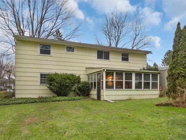 back of house with a sunroom and a lawn