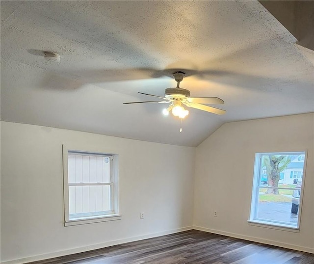 empty room featuring dark hardwood / wood-style floors, vaulted ceiling, and a textured ceiling