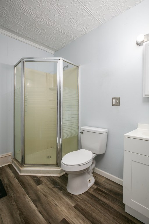 bathroom with toilet, vanity, a shower with door, and hardwood / wood-style floors