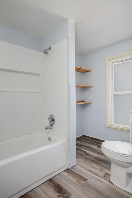 bathroom featuring hardwood / wood-style floors, tiled shower / bath combo, and toilet