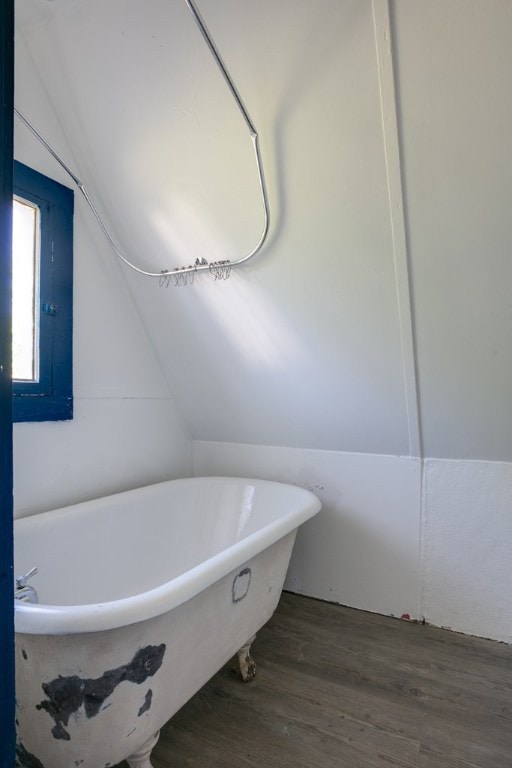 bathroom with lofted ceiling, hardwood / wood-style floors, and a tub