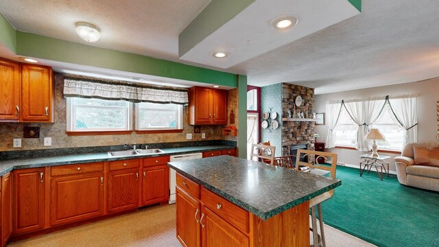 kitchen with sink, a center island, white dishwasher, a textured ceiling, and light colored carpet