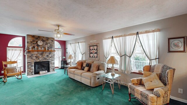 carpeted living room featuring ceiling fan, a stone fireplace, and a textured ceiling